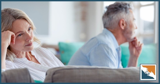 Older couple pondering on a couch in their home